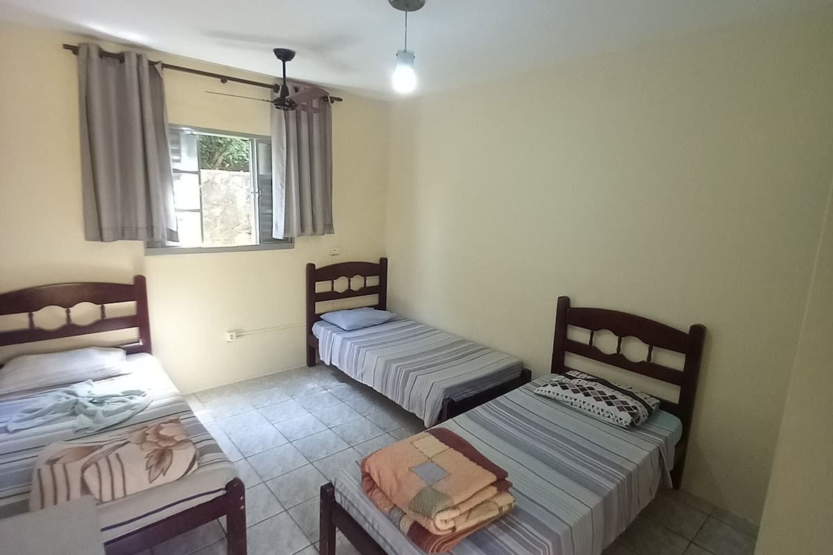 A room with two beds, a desk, and a window with curtains.