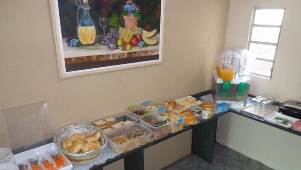 Un bufé de desayuno con diversas opciones de comida y un dispensador de jugo.