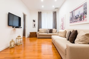 Relax in this stylish living room with a flat-screen TV, comfortable sofa, and large window.