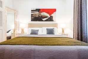 Relax in a serene space with a large bed, modern artwork, and a spacious area for unwinding.