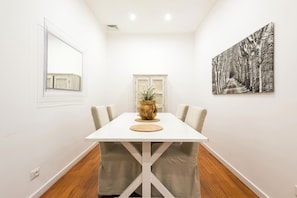 Enjoy meals in this inviting dining area with a beautifully set table and a stunning wall art.