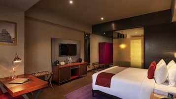Une chambre d’hôtel avec un lit, un bureau, une chaise, une télévision et un placard rouge.