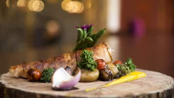 Un canard rôti, accompagné de légumes, présenté sur une planche en bois.