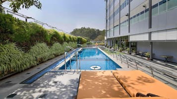Una piscina al aire libre, sillones reclinables de piscina