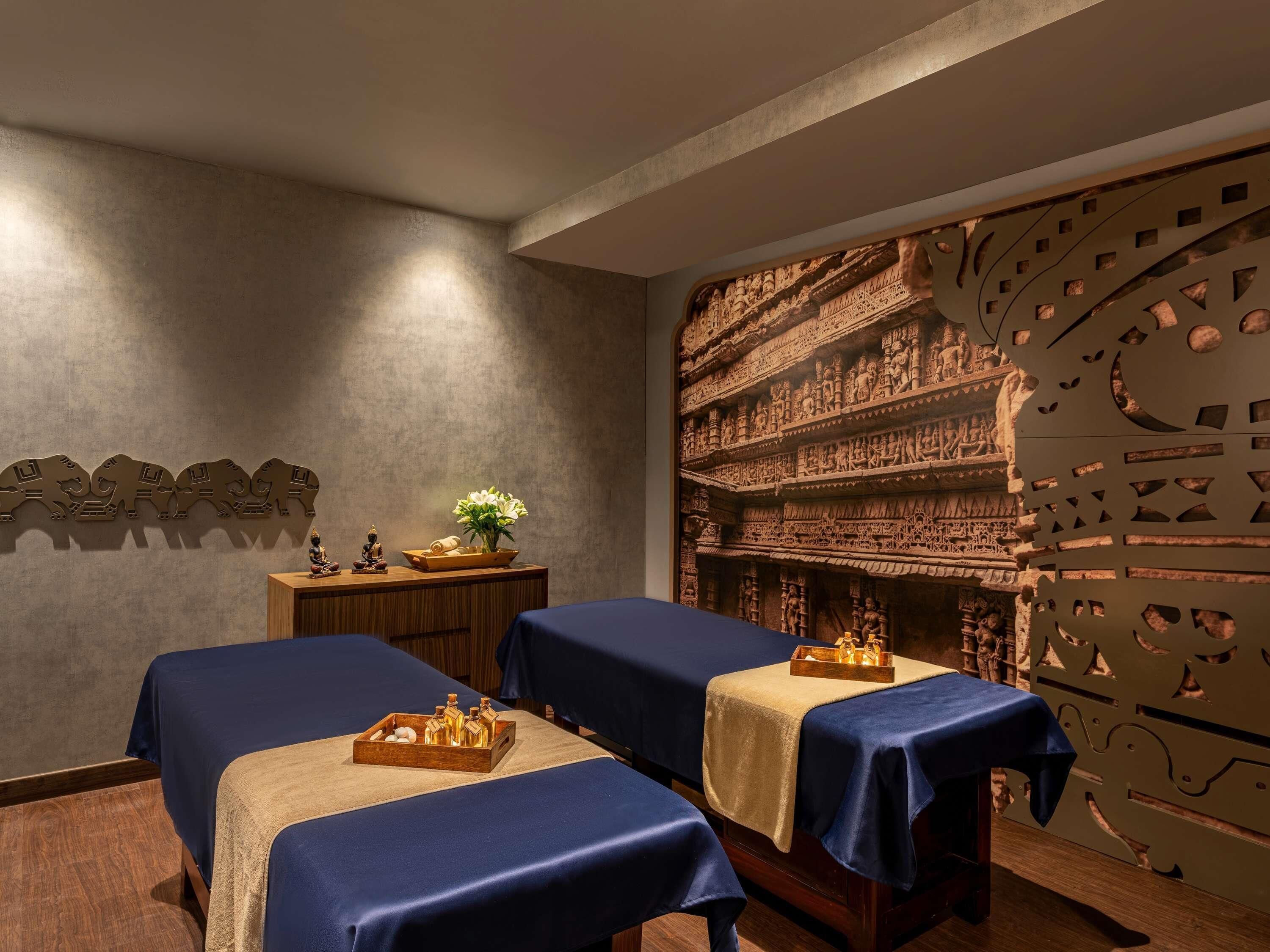 A room with two beds, a wall with carved artwork, and a decorative panel with geometric patterns.