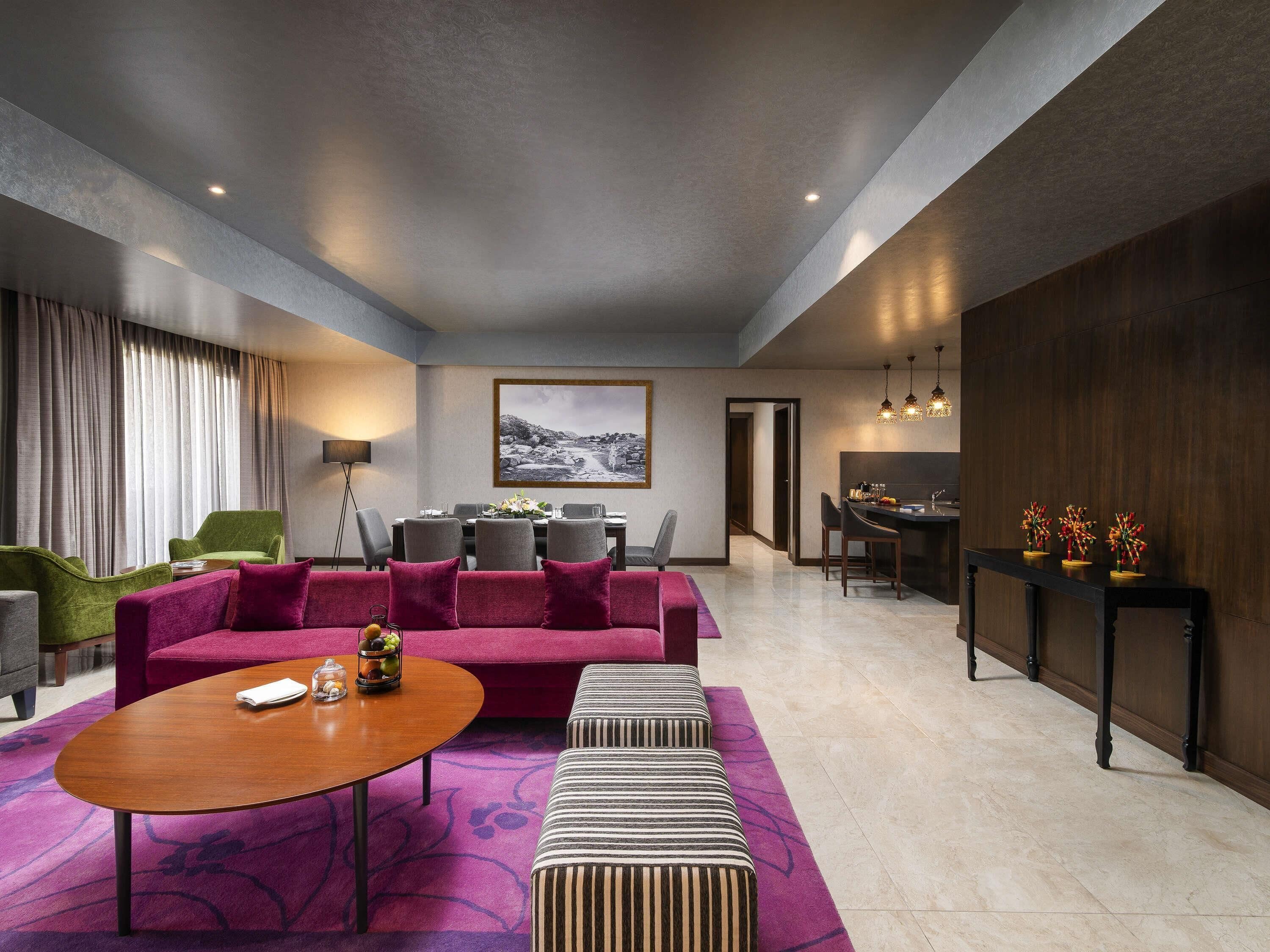 Een moderne hotelkamer met een zithoek, eethoek en uitzicht op de omgeving.