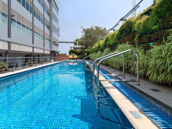 A swimming pool with a metal railing, a bench, and a building with a modern design. - Grand Mercure Bengaluru at Gopalan Mall- An Accor Hotels Brand (Bengaluru)