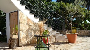 A modern outdoor area with a stone staircase, potted plants, and a metal table. - B&B Terra Marique (Syracuse)