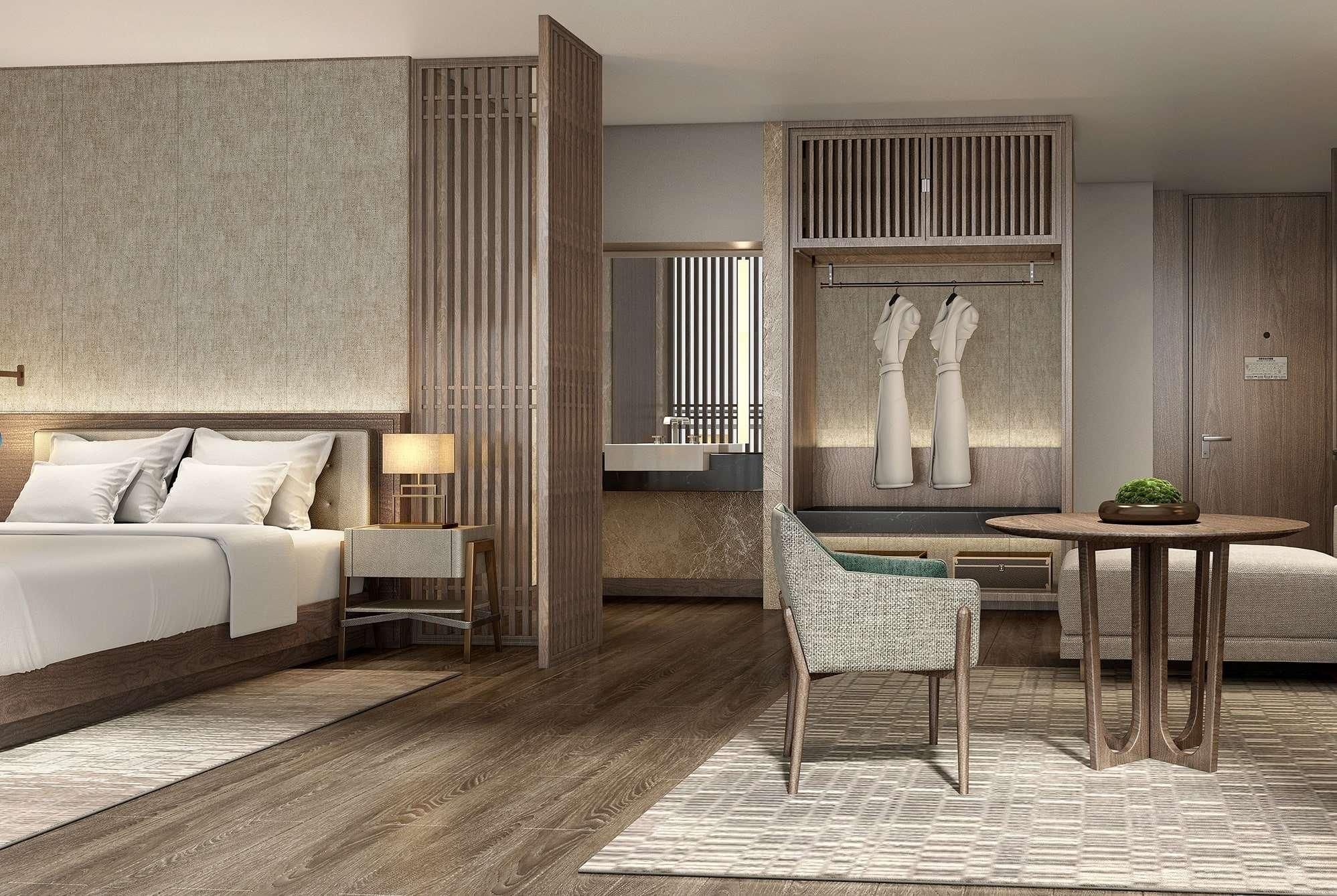 Una habitación de hotel moderna con una cama grande, una zona de estar con una mesa y sillas, y vistas de la ciudad a través de un ventanal.