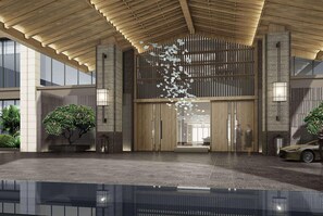 Una entrada de edificio moderna con techo de madera, grandes puertas de cristal y un elemento decorativo colgante.