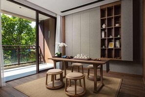 Un interior moderno con una mesa de madera, taburetes, una estantería y vistas a zonas verdes.