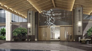 A modern building entrance with a wooden ceiling, large glass doors, and a decorative hanging element. - Wingate by Wyndham Hainan Chengmai (Chengmai)