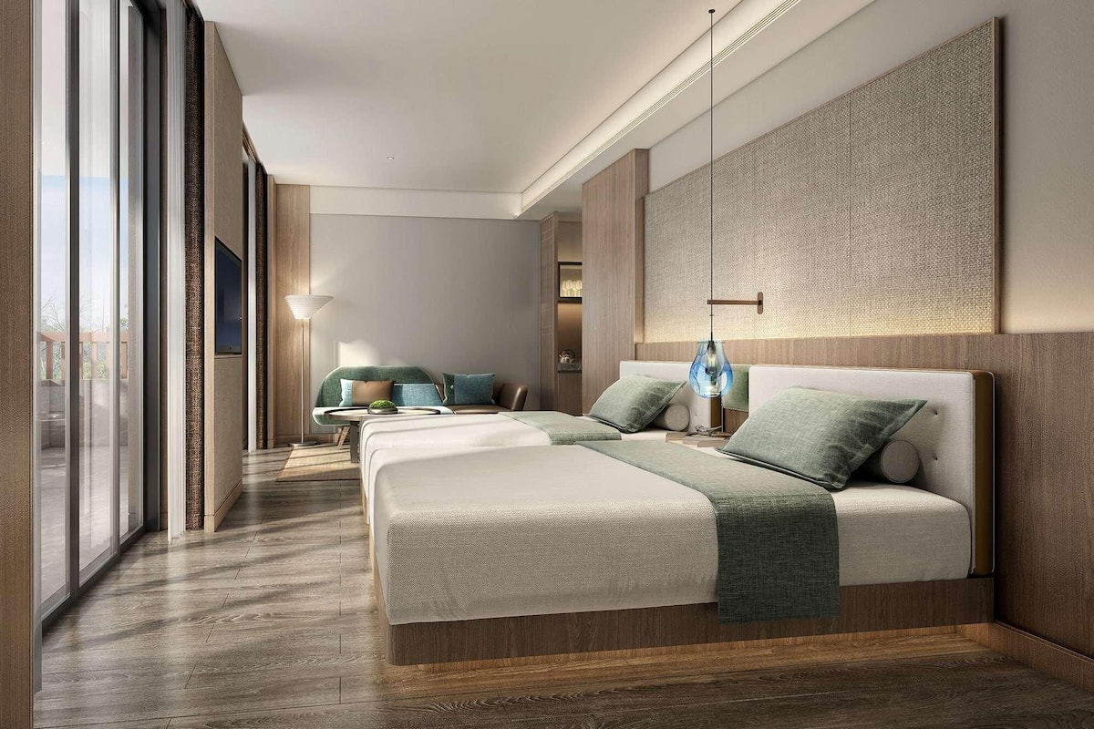 A modern hotel room with a large bed, a sofa, and a dining area.