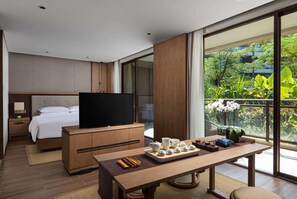 A modern hotel room with a bed, TV, dining table with tea set, and a balcony with plants. - Wingate by Wyndham Hainan Chengmai (Chengmai)
