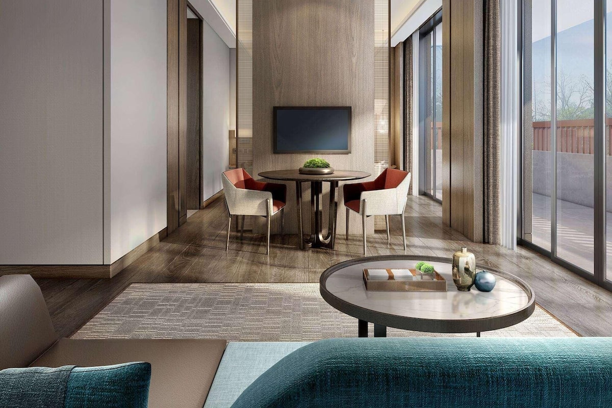 A modern interior with a dining area featuring a round table and chairs, a sofa with a throw pillow, and a coffee table with decorative items.