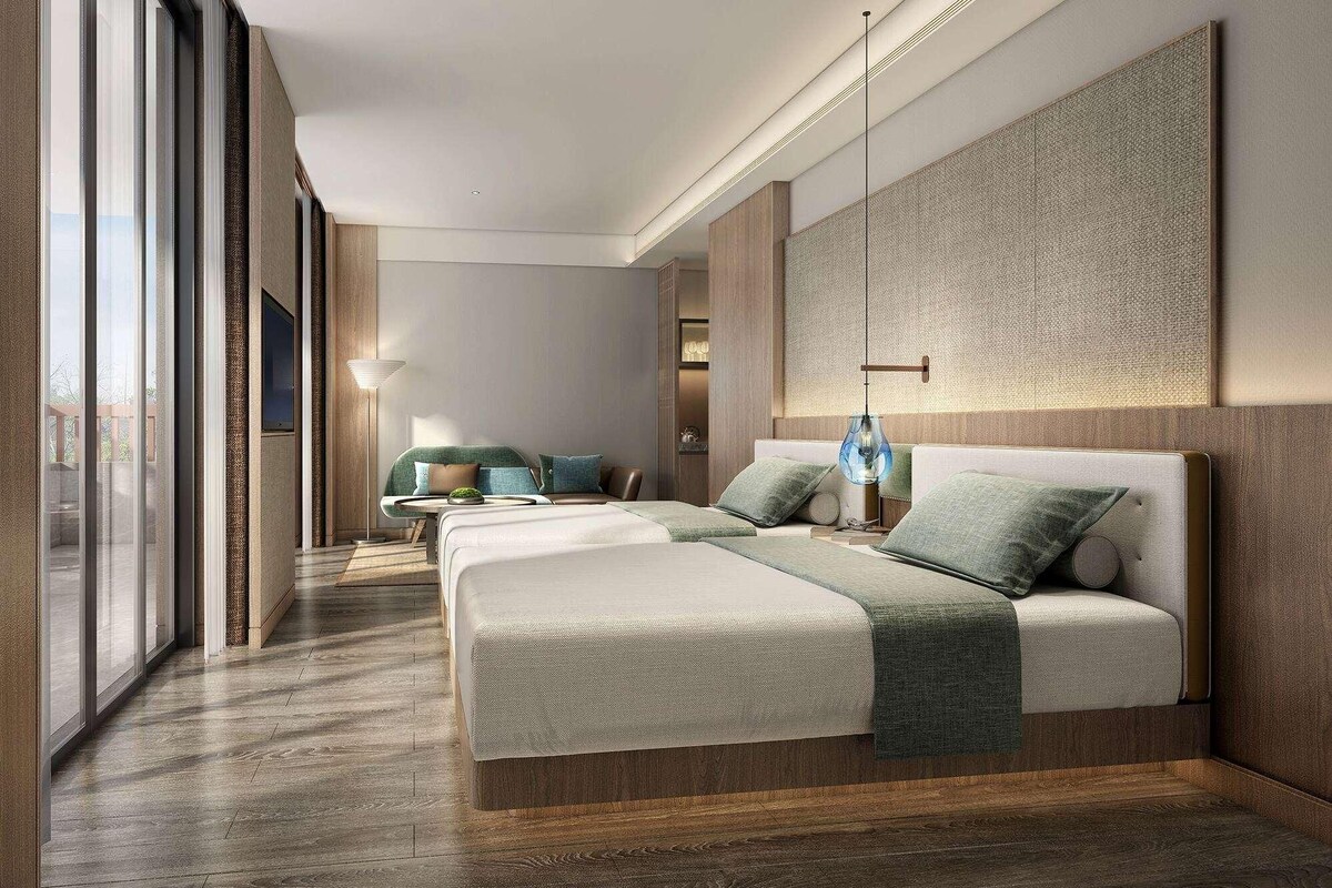 Una habitación de hotel moderna con una cama grande, zona de estar y vistas amplias por las ventanas.