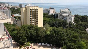 A high-rise hotel with multiple floors, a rooftop pool, and a view of the sea. - Apollo Spa Resort (Golden Sands)