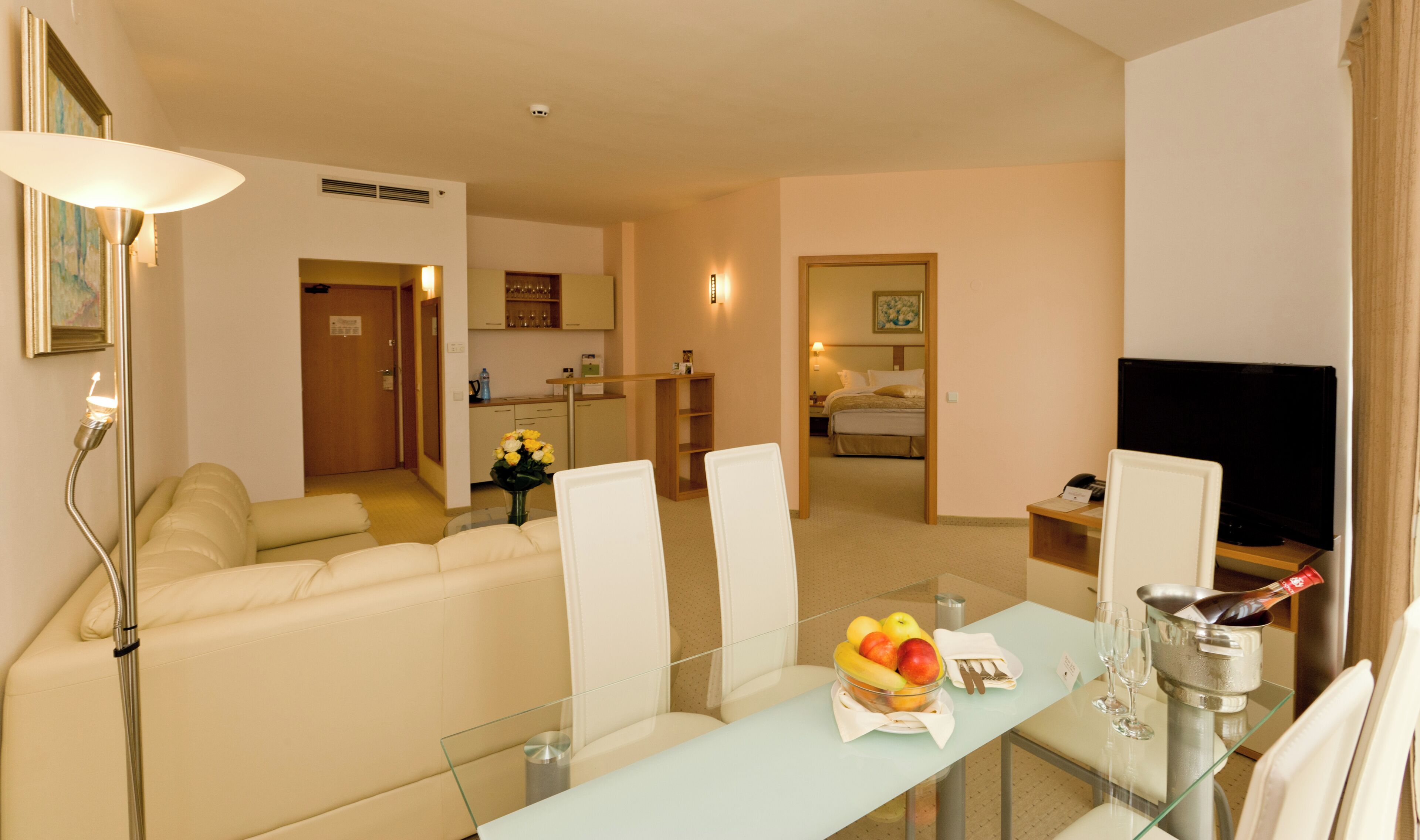 Une chambre d’hôtel comprenant un coin salon, une kitchenette et un lit.