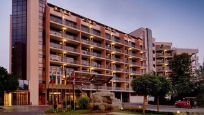 A multi-story hotel with balconies, a stone facade, and a well-lit entrance. - Apollo Spa Resort (Golden Sands)