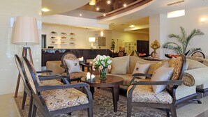 A spacious lobby with a high ceiling, a reception desk, and a seating area with patterned chairs and sofas. - Apollo Spa Resort (Golden Sands)