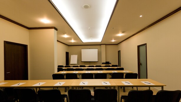 A conference room with a long table, chairs, a whiteboard, and a projector screen. - Apollo Spa Resort (Golden Sands)