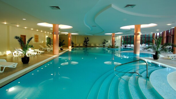An indoor swimming pool with lounge chairs and potted plants. - Apollo Spa Resort (Golden Sands)