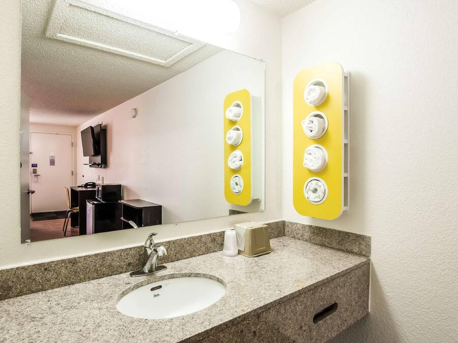 A hotel bathroom with a sink, mirror, and towel warmer.
