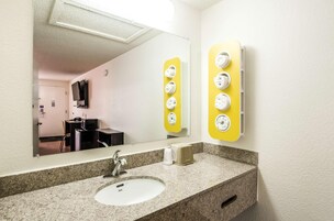 Un baño de hotel con lavamanos, espejo y calentador de toallas.
