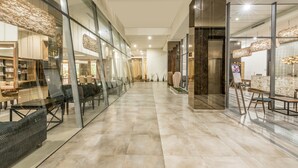 Un hall d’entrée spacieux, avec un long couloir, des murs en verre et un mobilier moderne.