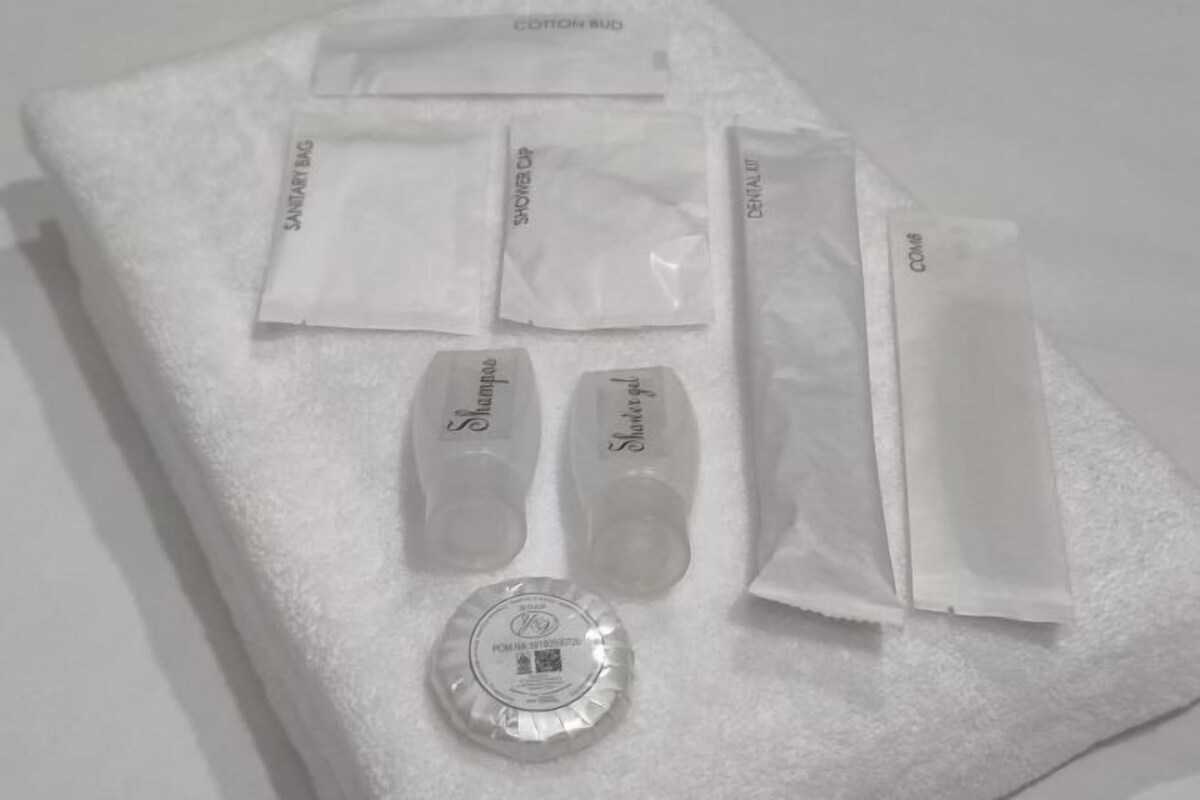 A white towel with various toiletries including shampoo, conditioner, and a bottle of lotion.
