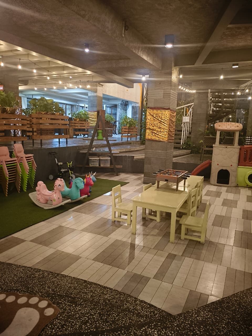 An indoor play area with a foosball table, seating, and a small pool table.