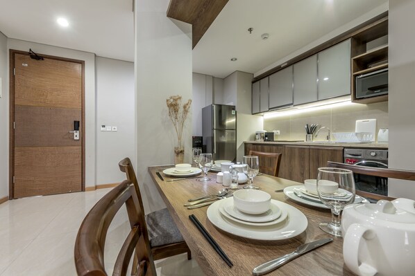 A modern kitchen with stainless steel appliances, wooden cabinets, and a dining area set for a meal.