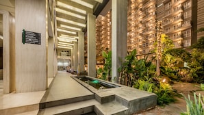 Un hall d’hôtel comprenant un comptoir d’accueil, une piscine et un escalier menant aux étages supérieurs.