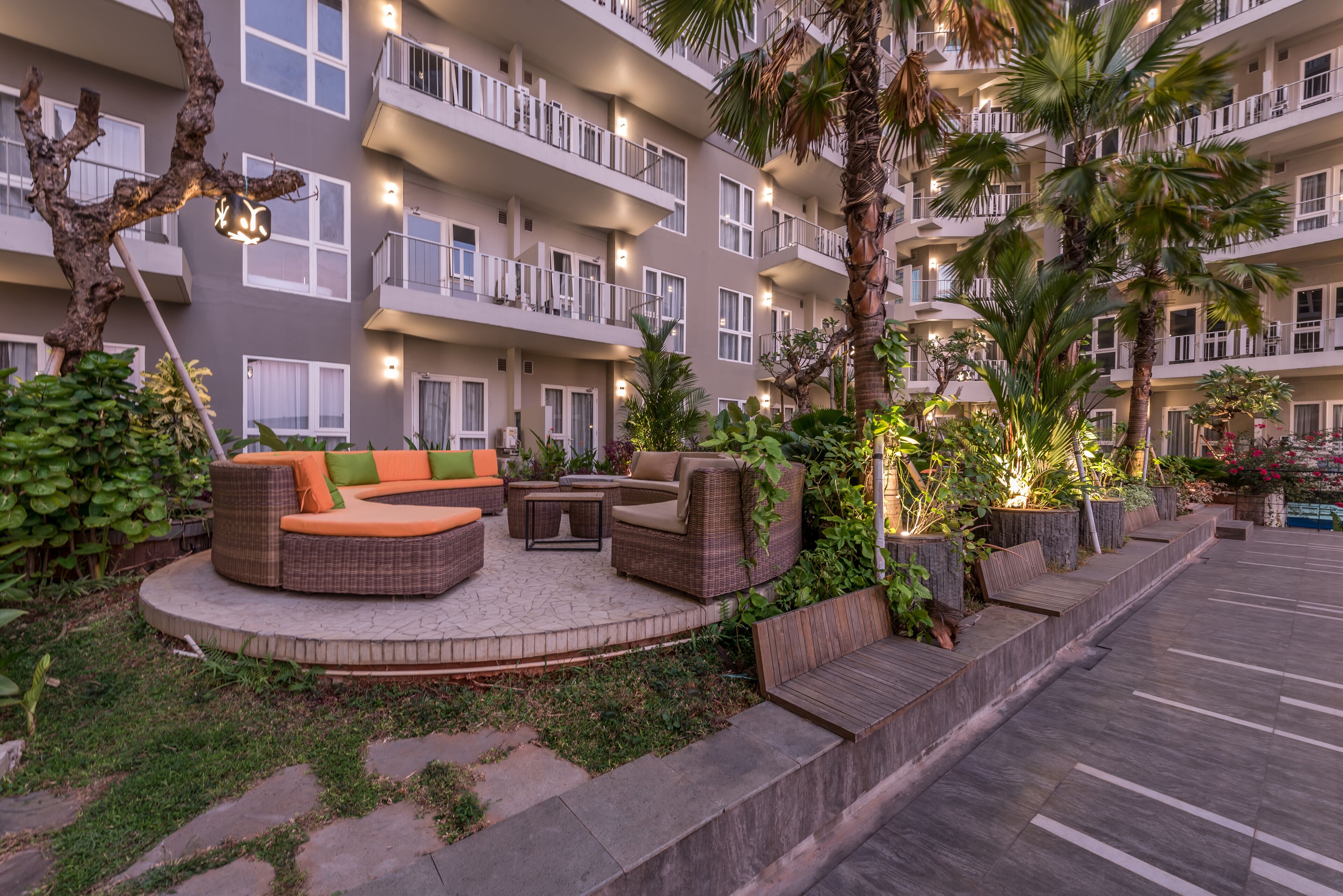 Une cour avec des sièges en plein air, un palmier et un immeuble à plusieurs étages doté de balcons.