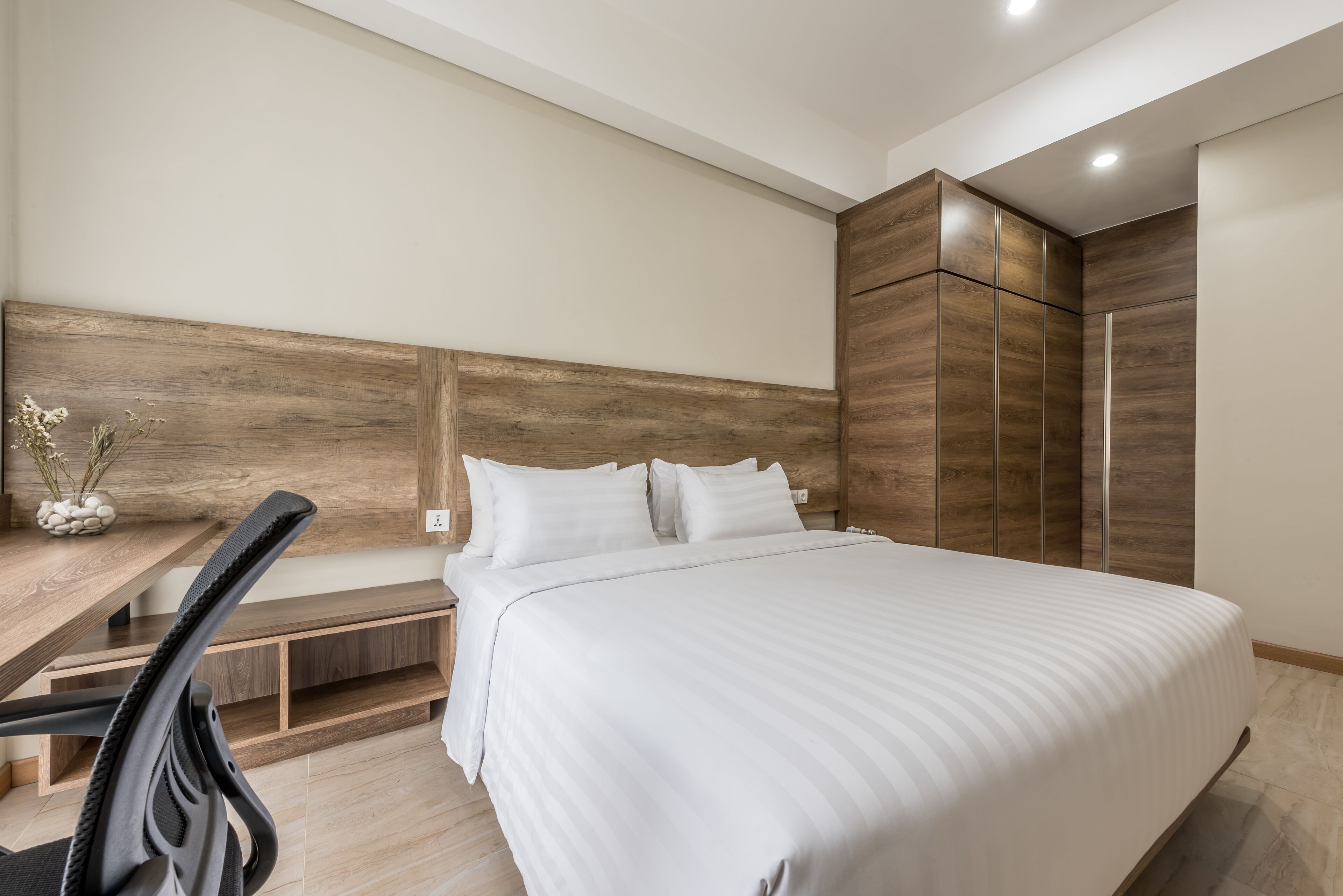 Un dormitorio moderno con una cama grande, cabecera de madera y armario empotrado.