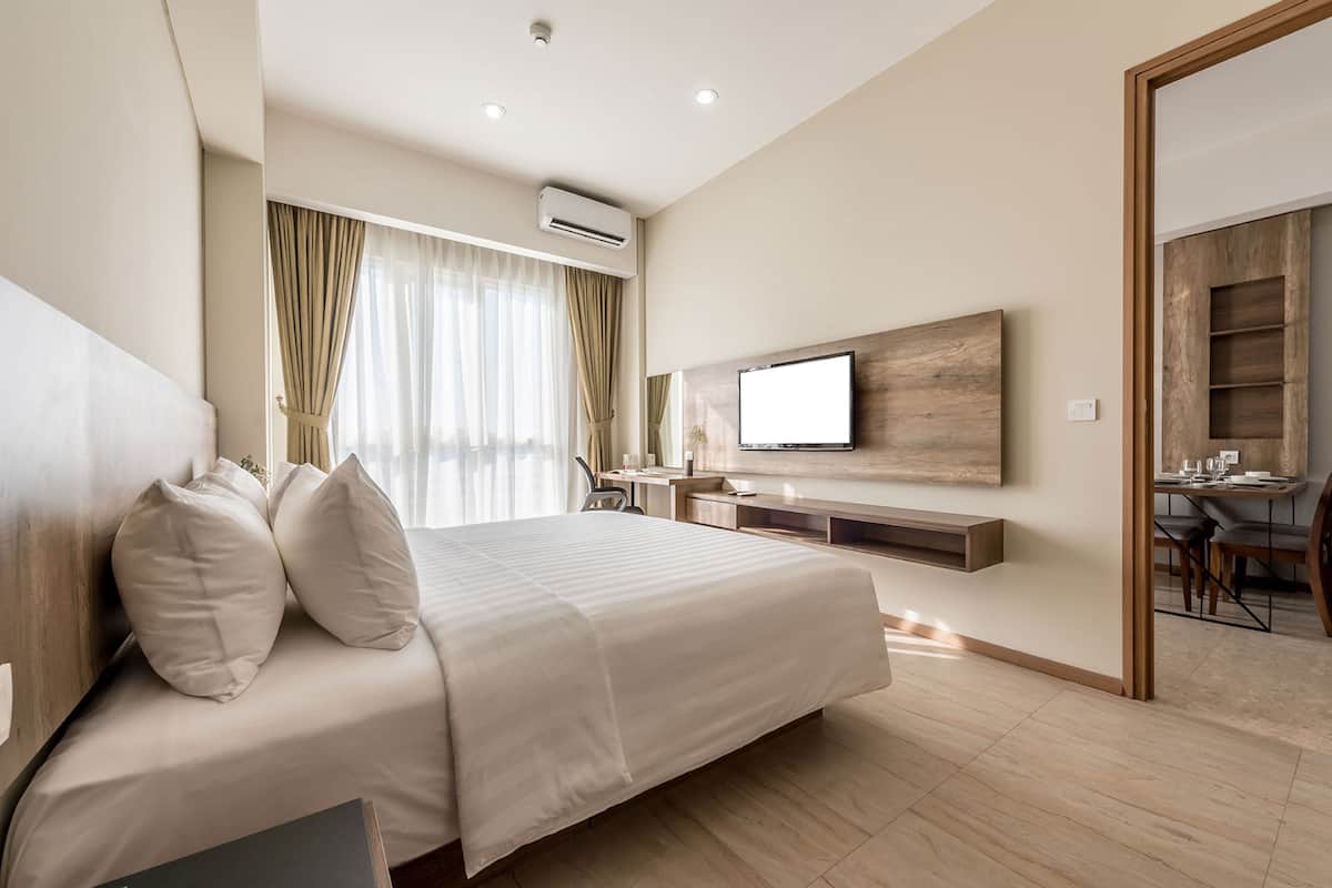 Ein modernes Hotelzimmer mit einem großen Bett, einem Schreibtisch und einem an der Wand befestigten Fernseher.