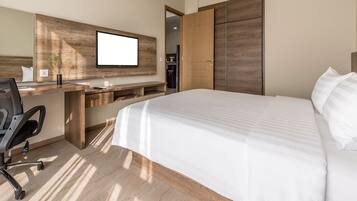 A modern hotel room with a large bed, a desk with a chair, a TV mounted on the wall, and a wardrobe.