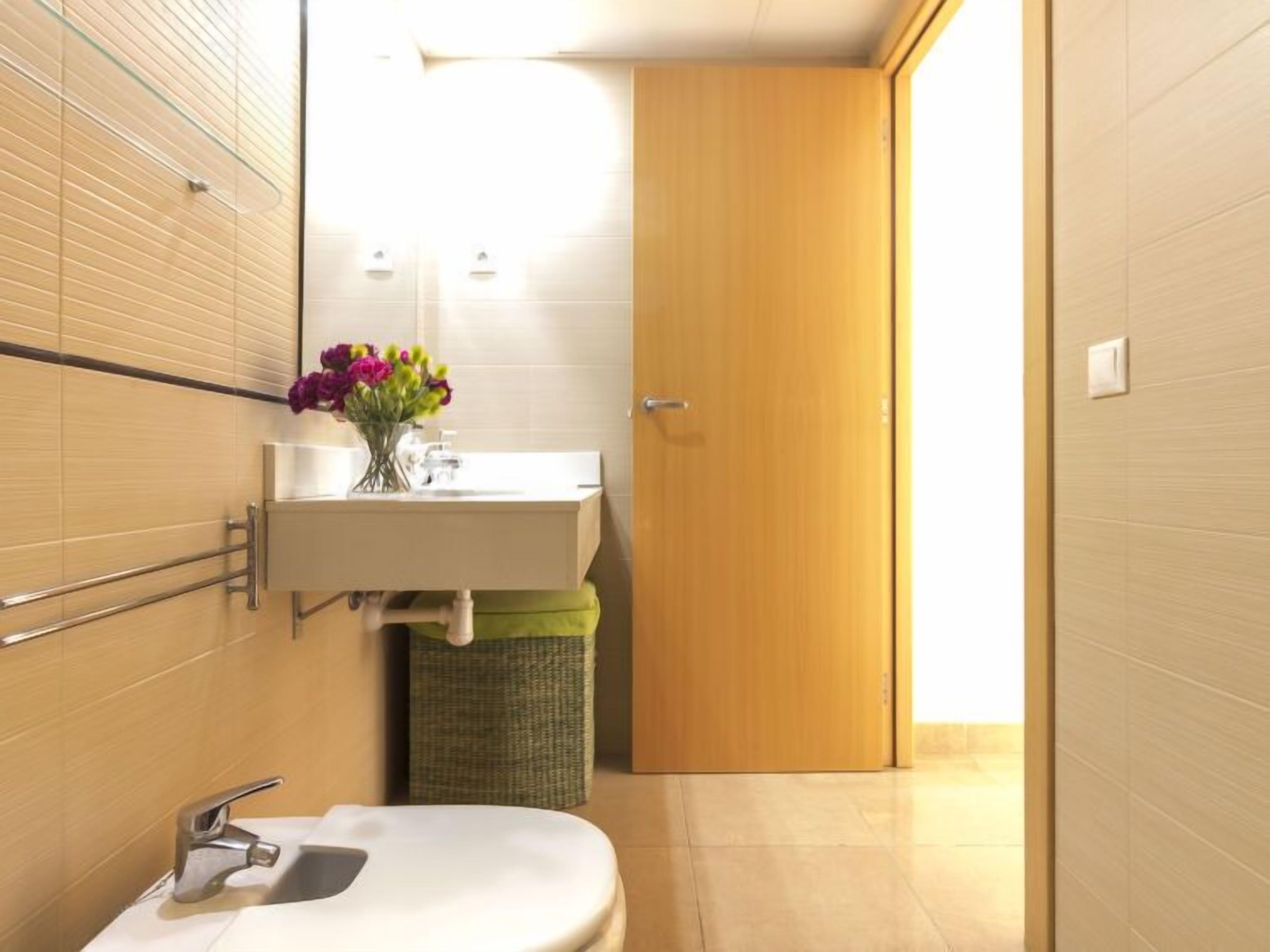 A bathroom with a sink, mirror, and a wooden door.