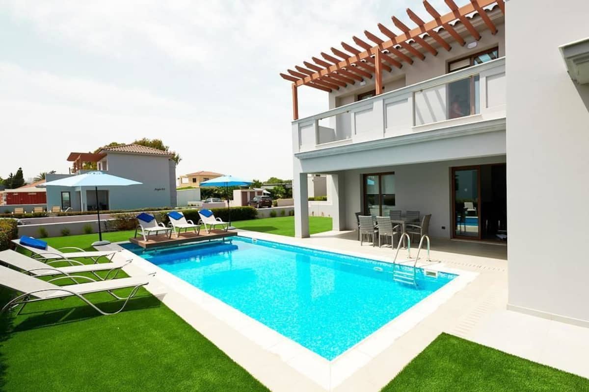 Ein moderner Außenpool mit einer Pergola, Liegestühlen und einer Terrassenanlage.