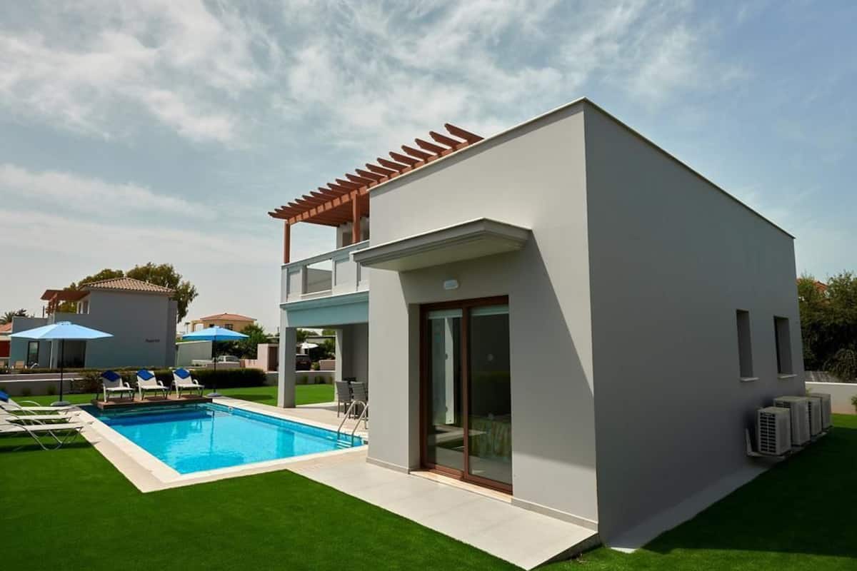 Ein modernes, zweistöckiges Haus mit Swimmingpool, einer Pergola und einer überdachten Terrasse.