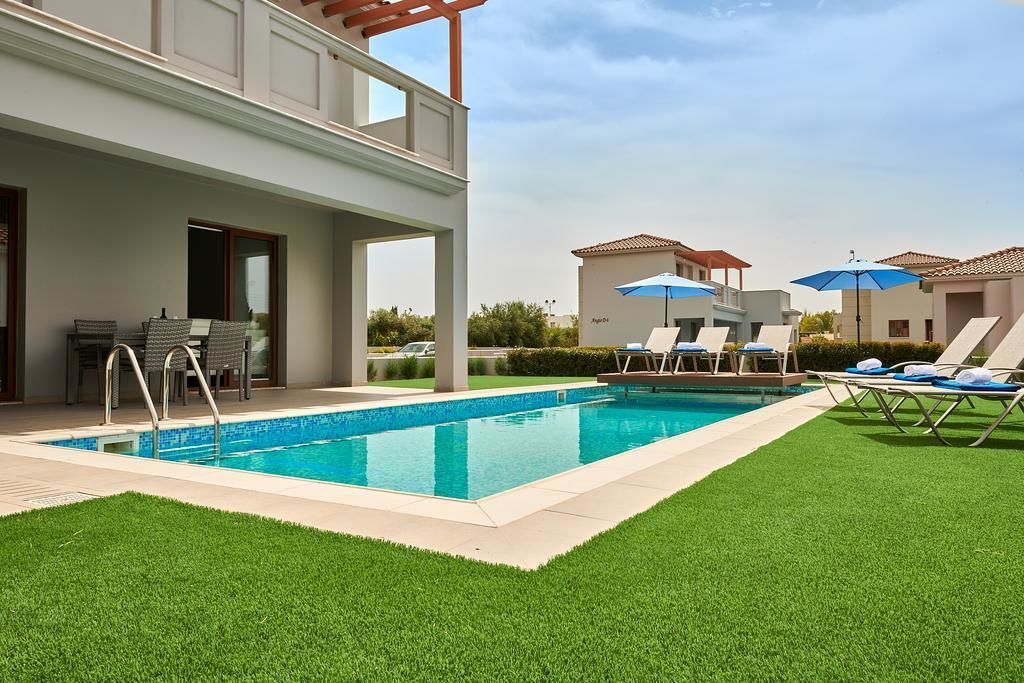 A modern outdoor pool area with a clear blue pool, lounge chairs, and umbrellas.