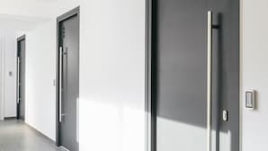 A modern hallway with doors marked with numbers, a clean floor, and a minimalist design. - Evapollo (Thessaloniki)