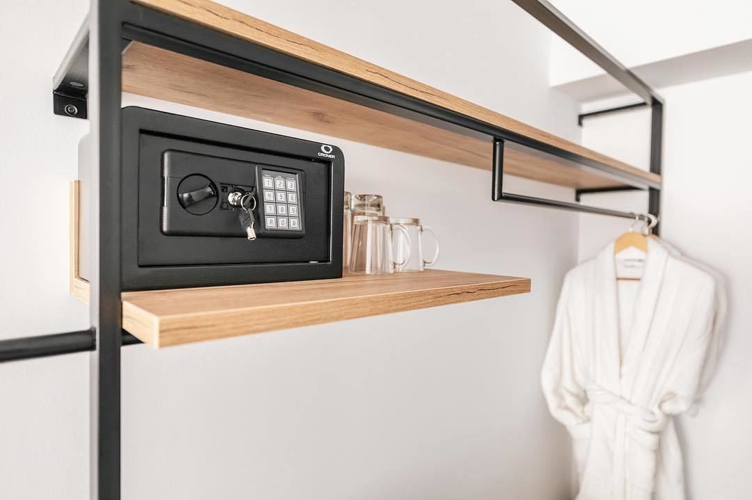 A secure storage unit with a combination lock, a wooden shelf, and a hanging robe.