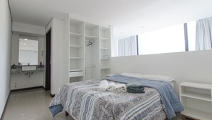 A bedroom with a bed, a built-in wardrobe, a vanity with a mirror, and a window with curtains. - PrimeTime Depto en Las Mercedes (Asunción)