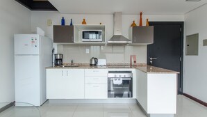 A modern kitchen with white cabinets, a microwave, a stove, and a dishwasher. - PrimeTime Depto en Las Mercedes (Asunción)