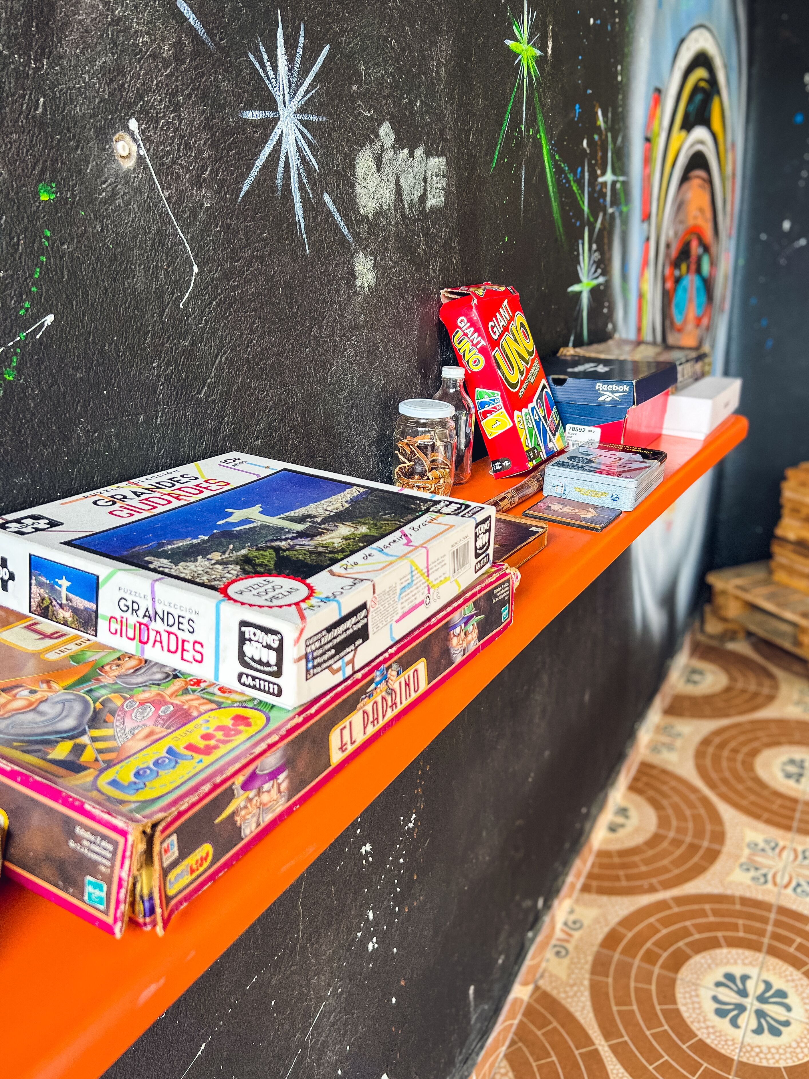 A shelf with board games and puzzles, a Reebok box, and a giant Uno card.