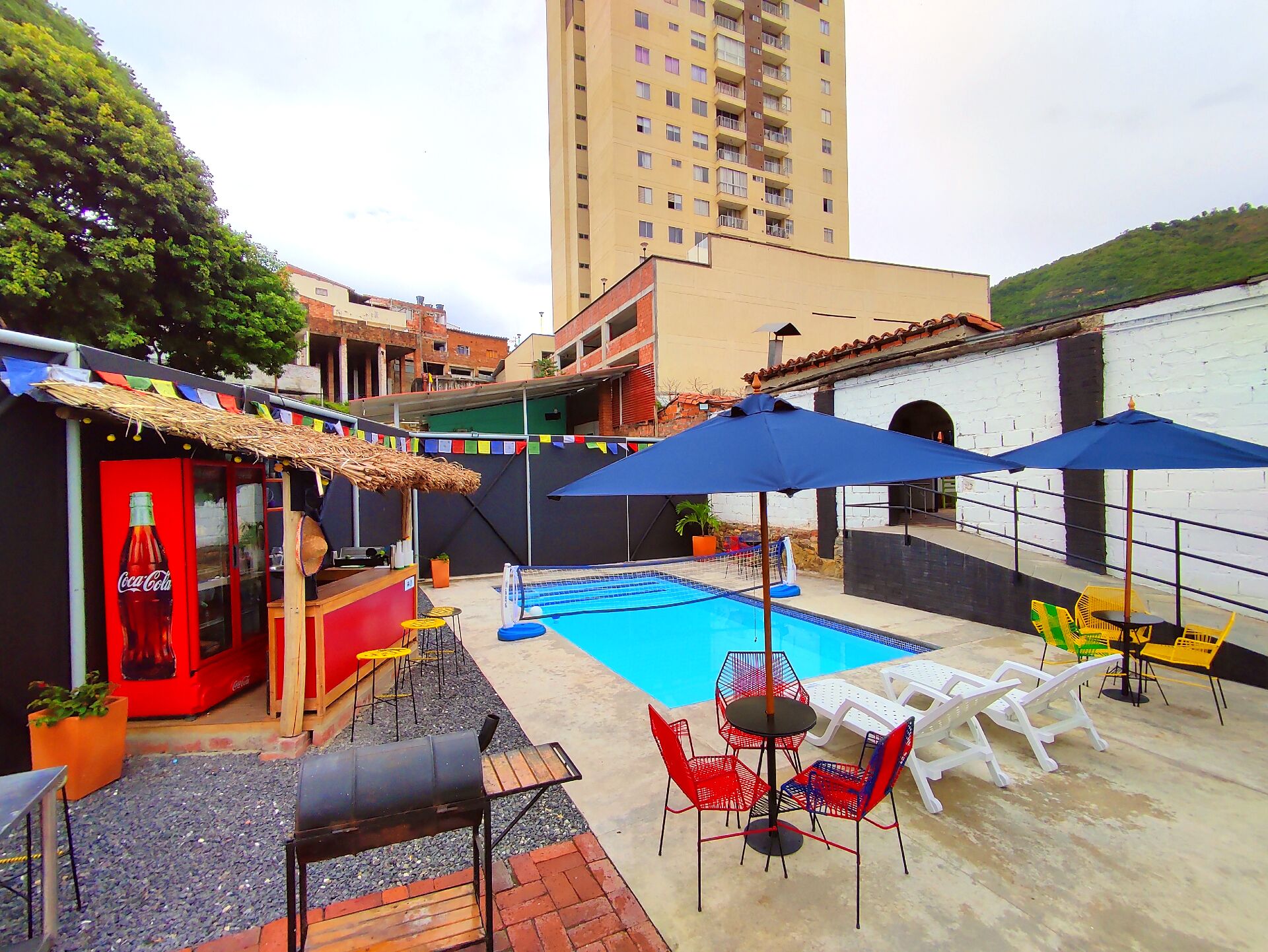 A pool area with a barbecue setup, lounge chairs, and a Coca-Cola advertisement.