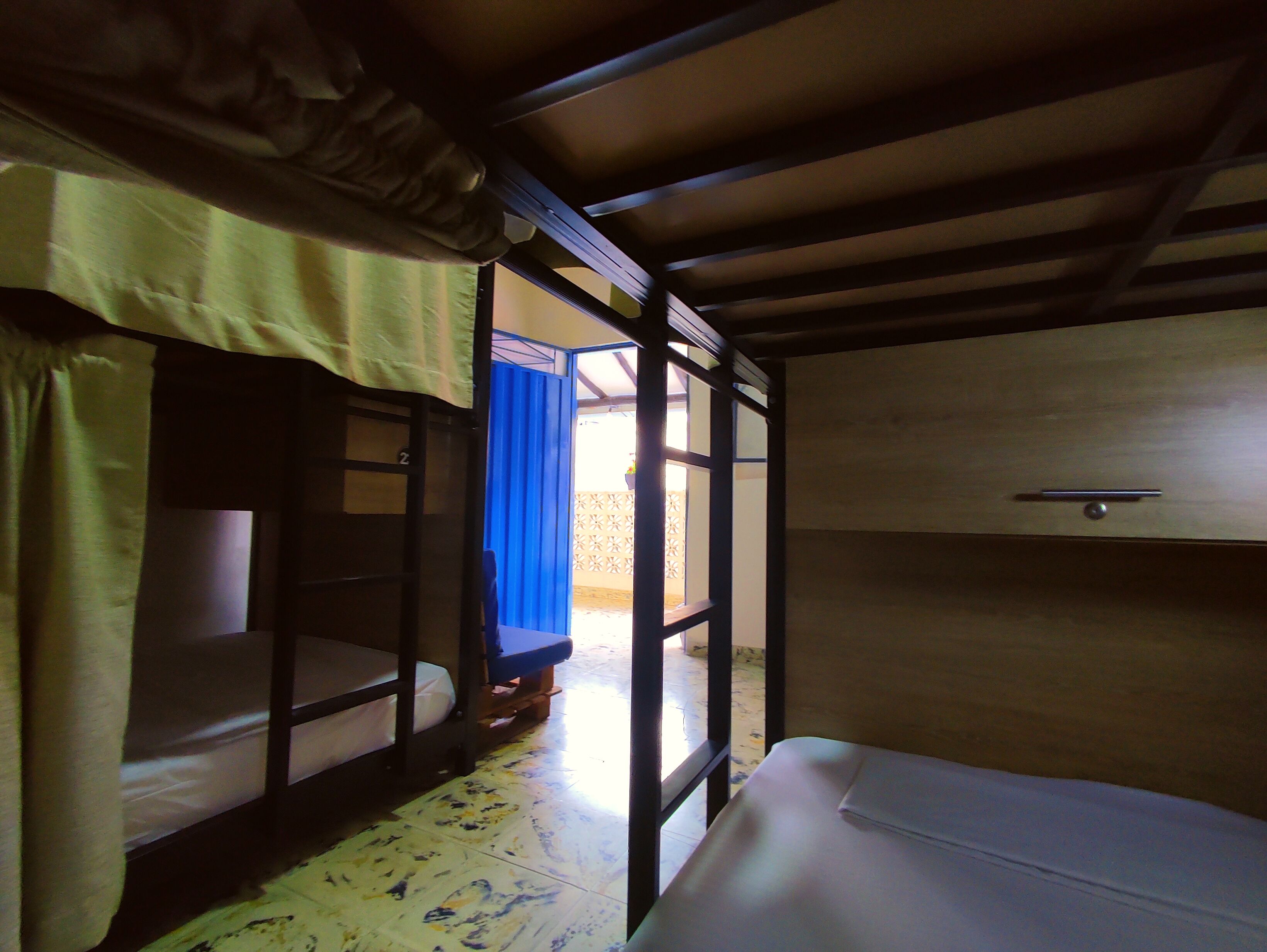 A room with bunk beds, a wooden ceiling, and a small table with a drawer.