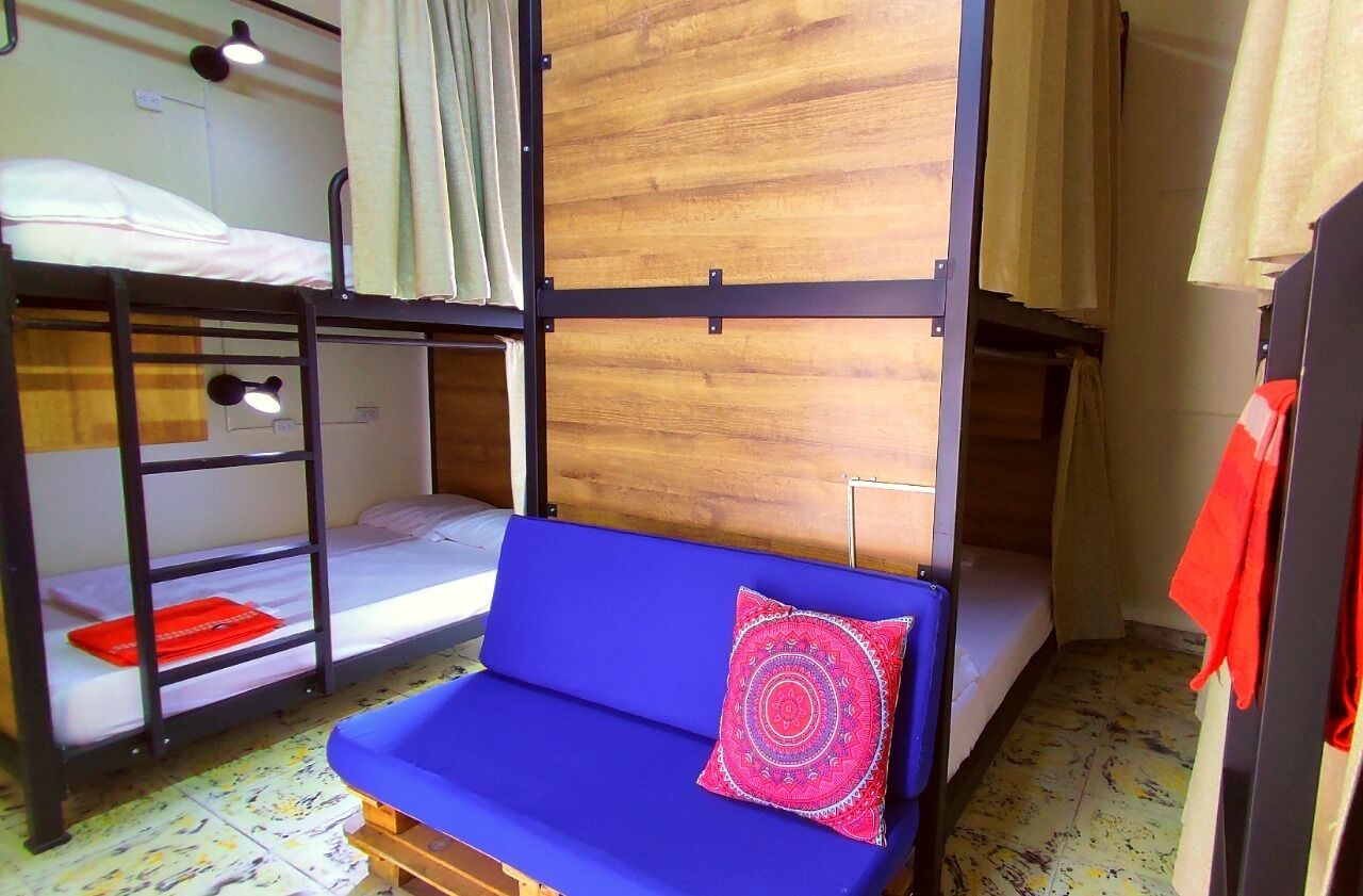 Un dormitorio con literas, un sofá azul y una pared divisoria de madera.