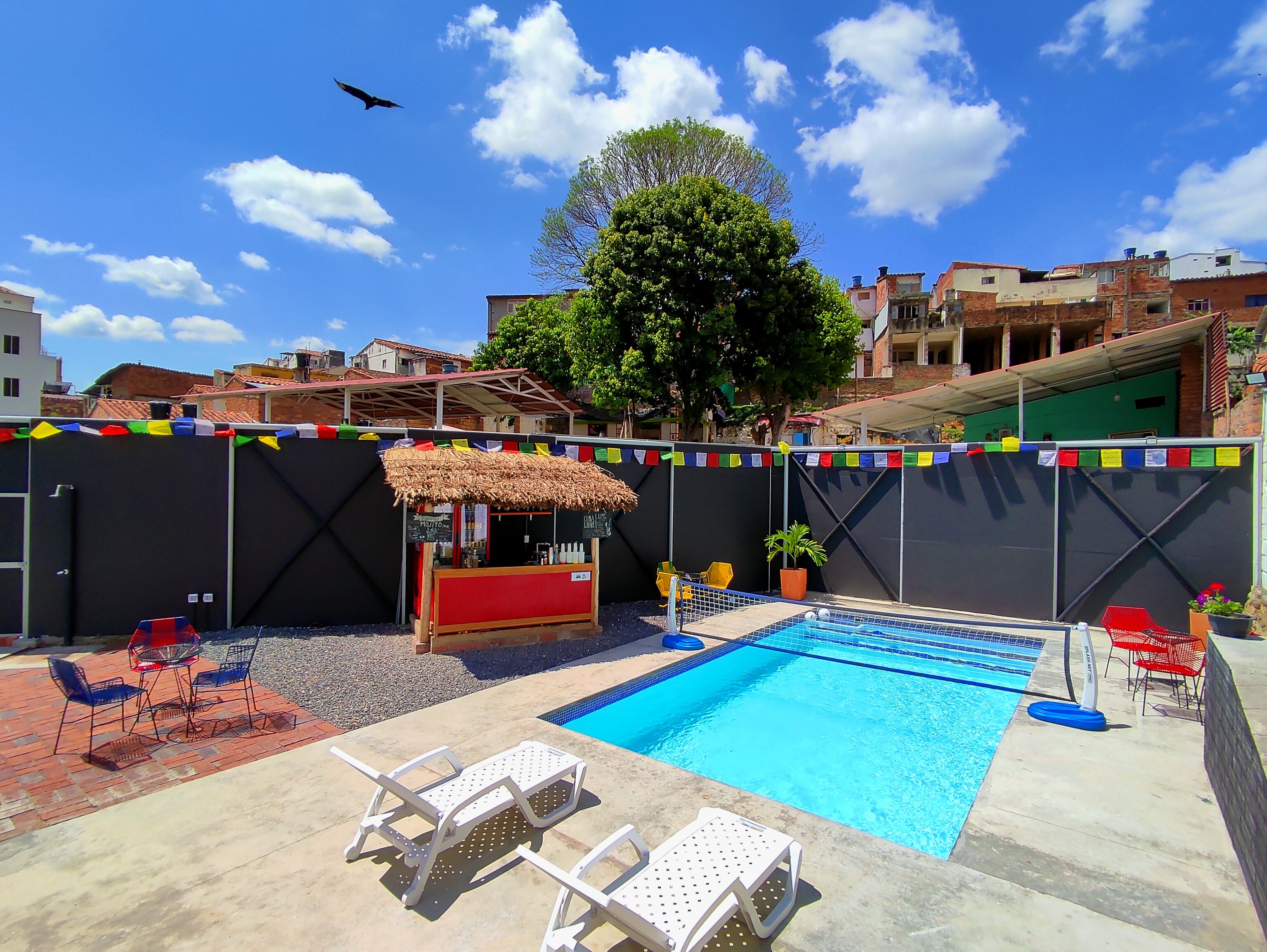A swimming pool with lounge chairs, a small bar, and colorful flags.